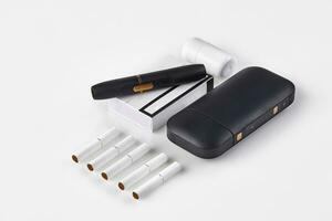 Nouveau génération noir électronique cigarette et batterie, nettoyeur, un pack et cinq bâtons chauffants isolé sur blanche. chauffage le tabac système. proche en haut photo