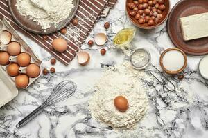 fermer tir. Haut vue de une cuisson Ingrédients et ustensiles de cuisine sur le marbre table Contexte. photo