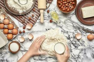 fermer tir. Haut vue de une boulanger cuisinier lieu, mains sont travail avec une brut pâte sur le marbre table Contexte. photo