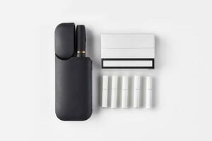 Nouveau génération noir électronique cigarette dans ouvert batterie, un paquet, cinq bâtons chauffants isolé sur blanche. salut-technologie chauffage le tabac système. proche en haut photo