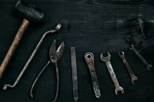 vieux, rouillé outils mensonge sur une noir en bois tableau. marteau, ciseau, métal ciseaux, clé. photo