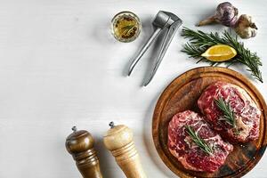 brut du boeuf steak avec épices et Ingrédients pour cuisine sur en bois Coupe planche et blanc Contexte. photo