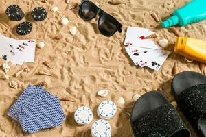 poker de plage. frites et cartes sur le sable. autour le coquillages, des lunettes de soleil et retourner flops. Haut vue photo