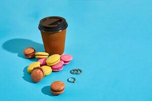 chaud café dans marron papier tasse avec noir couvercle et macarons sur bl photo