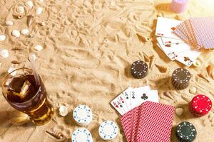 poker de plage. frites et cartes sur le sable. autour le coquillages et du froid boisson dans une verre. Haut vue photo