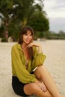 attrayant brunette femme dans élégant décontractée été tenue posant sur le tropical plage pendant les vacances. photo