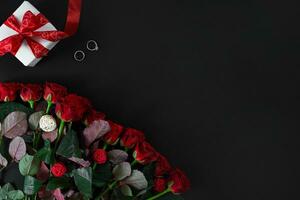 rouge des roses, bague et cadeau boîte sur noir Contexte photo