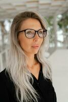 intérieur portrait de élégant affaires femme dans des lunettes posant dans sa moderne bureau. photo