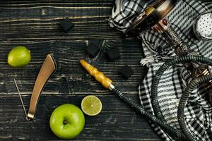 arabe narguilé avec une le tabac saveur de une mélange de citron vert et Pomme. Haut vue de une foncé en bois Contexte photo