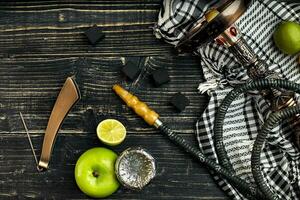 arabe narguilé avec une le tabac saveur de une mélange de citron vert et Pomme. Haut vue de une foncé en bois Contexte photo