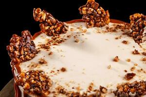 rond blanc gâteau avec caramel et Chocolat gonflé riz sur une rond plateau sur noir Contexte photo