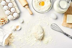 brut pâte prêt pour pétrissage sur blanc tableau. boulangerie ingrédients, œufs, farine, beurre. formes pour fabrication biscuits. photo