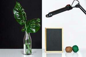 le élégant intérieur avec moquer en haut affiche cadre, feuilles dans verre bouteille sur table avec noir et blanc mur sur Contexte. photo