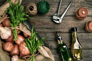 Frais patates, huile, Ail et épicé herbes sur une cuisine en bois Contexte. photo