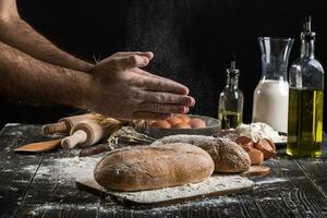 chef arrose Frais pain avec farine. homme en train de préparer pâte à table dans cuisine. photo