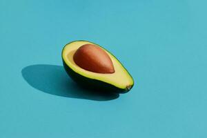 coloré fruit modèle de Frais coupé Avocat moitiés avec fosses sur bleu pastel Contexte photo