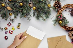 Noël table avec divers articles. femme mains en mettant une lettre dans un enveloppe. photo