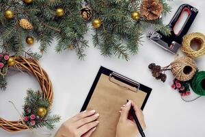 Créatif Noël DIY. femme fabrication Fait main Noël couronne. Accueil loisirs, outils, babioles et détails pour vacances décorations sur blanc table Contexte. Haut vue photo