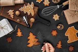femme décorer pain d'épice Noël biscuits avec glaçage sucre. Noël les préparatifs concept. Haut vue avec copie espace. photo