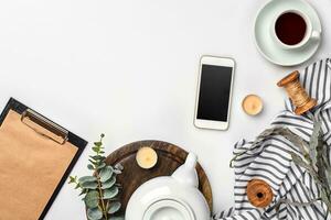 encore la vie avec thé tasse et le Contenu de une espace de travail composé. différent objets sur blanc tableau. plat allonger photo