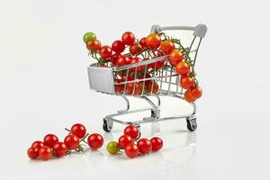 mini achats Chariot plein avec Cerise tomates sur blanc Contexte photo