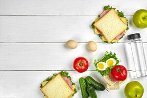 déjeuner. des sandwichs et Frais légumes, bouteille de l'eau et vert Pomme sur en bois tableau. en bonne santé en mangeant concept. Haut vue photo