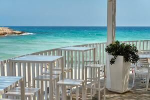 fermer coup de une agréable café avec blanc chaises et les tables situé à le plage de le Azur méditerranéen mer, entouré par une magnifique la nature de Chypre. ayia Napa. photo