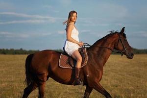 femme en robe à cheval sur un cheval brun