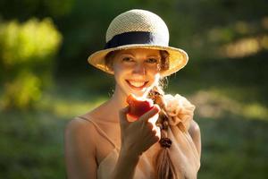 femme heureuse au chapeau mangeant une pomme photo