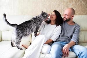jeune homme et femme avec leur chat sur le canapé à la maison photo