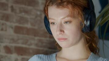 Jeune femme blanche assise avec un casque, regardant une tablette sur les genoux photo