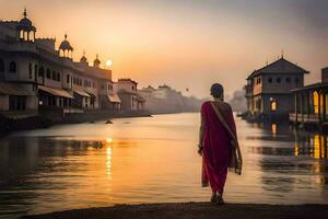 une femme dans une rouge sari des stands sur le bord de une rivière à le coucher du soleil. généré par ai photo