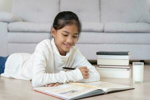 fille apprendre à maison. faire devoirs, encourager pour examen. Asie fille content école à la maison, éducation, pratique, technologie livre, étude, enfant, cours pour asiatique les enfants photo