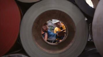 une équipe de Jeune Hommes travail dans une entrepôt stockage Rouleaux de métal feuilles. inspecter le métal feuille Rouleaux stockée dans le entrepôt à être importé sur le métal feuille production doubler. photo