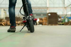 un électrique scooter est garé dans une grand usine entrepôt. il est nécessaire pour le commodité de le usine directeur. photo