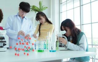 dans le science Salle de classe, un asiatique enfant scientifique expérimenter avec scientifique formules avec produits chimiques photo