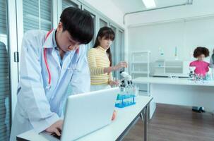 dans le science Salle de classe, un asiatique enfant scientifique expérimenter avec scientifique formules avec produits chimiques photo