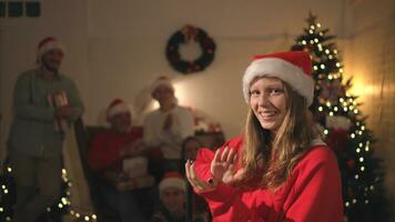 portrait de adolescent fille dans Père Noël chapeau séance sur chaise dans de face de Noël arbre, joyeux Noël et content vacances photo