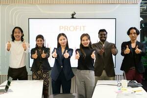 une groupe de multiracial hommes d'affaires donne le les pouces en haut dans de face de le réunion chambre, indiquant le concept de affaires succès. photo