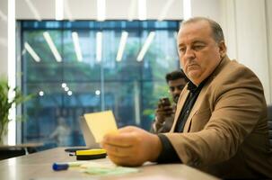 Sénior homme d'affaire travail avec les documents et mature homme d'affaire travail sur portable ordinateur dans Bureau photo