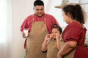 une grande taille famille avec une père portant une prothétique jambe, manger ensemble après cuisine et fille les boissons Lait pour santé dans le à manger pièce de le maison photo