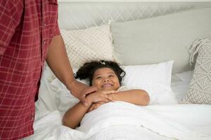 une grande taille famille avec une père portant une prothétique jambe, accalmie fille à sommeil sur le lit dans le chambre de le maison photo