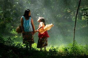 deux les filles asiatique femmes avec traditionnel Vêtements supporter dans le forêt tropicale. elles ou ils avait amusement en jouant ensemble avant assistant grand-père dans contagieux poisson dans une proche lac. photo