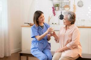 souriant femelle infirmière donnant tasse de Lait à Sénior femme à Accueil photo
