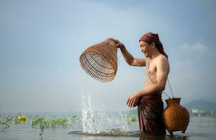 pêcheur en utilisant traditionnel pêche équipement à capture poisson pour cuisson, rural Thaïlande vivant la vie concept photo