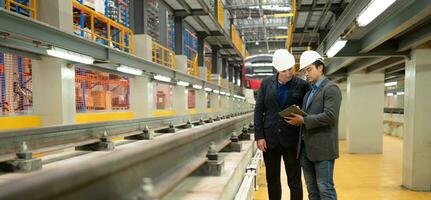 deux les hommes d'affaires inspecter rail travail à réserve équipement pour utilisation dans réparer des pistes et machinerie de le électrique train transport système. photo