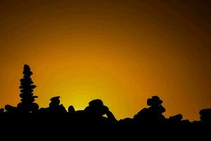 une groupe de empilés rochers dans de face de un Orange ciel photo