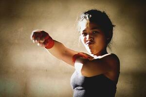 Jeune femme pratiquant boxe à le salle de sport, elle porte boxe gants. photo