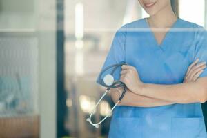 femelle médecin dans uniforme en portant une stéthoscope attendre à examiner une patient. une femelle médecin détient une stéthoscope à préparer pour traiter les patients dans le hôpital. copie espace pour insertion médical texte photo