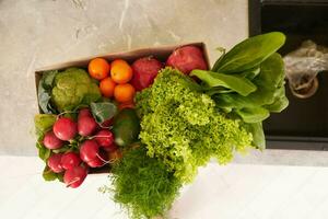 Haut vue de une recyclable papier carton boîte avec Frais biologique surgir de des fruits, des légumes et légumes verts sur le cuisine compteur photo